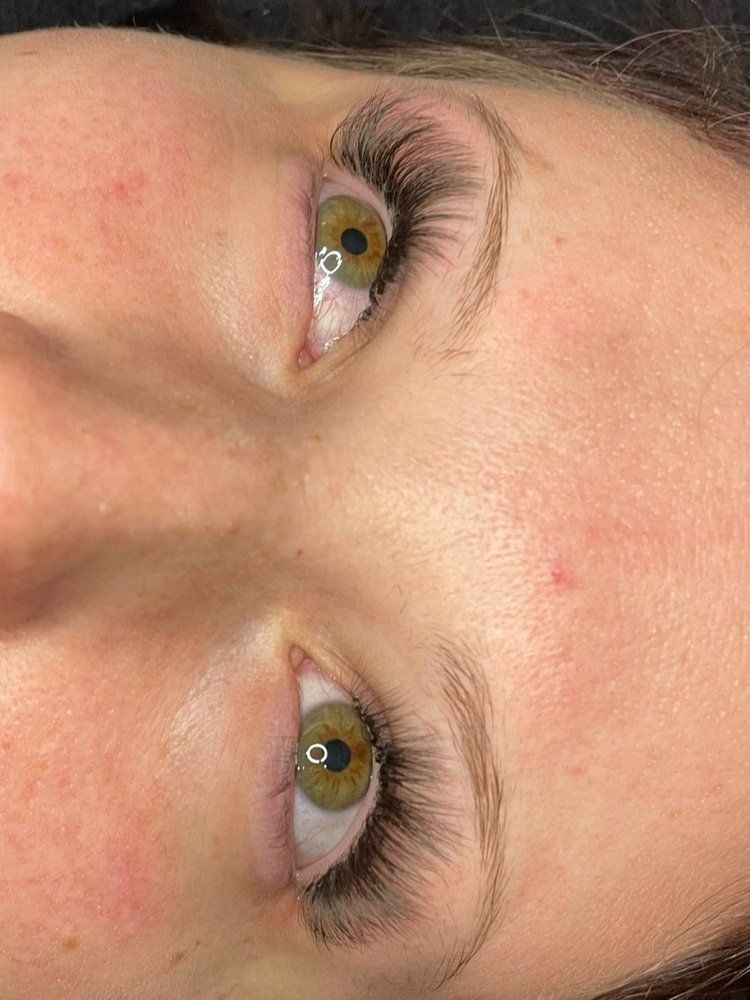 A close up of a woman 's face with green eyes and long eyelashes.