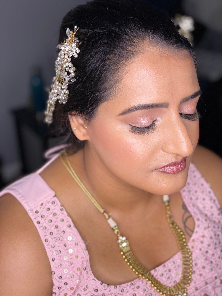 A woman is wearing a pink top and a gold necklace.