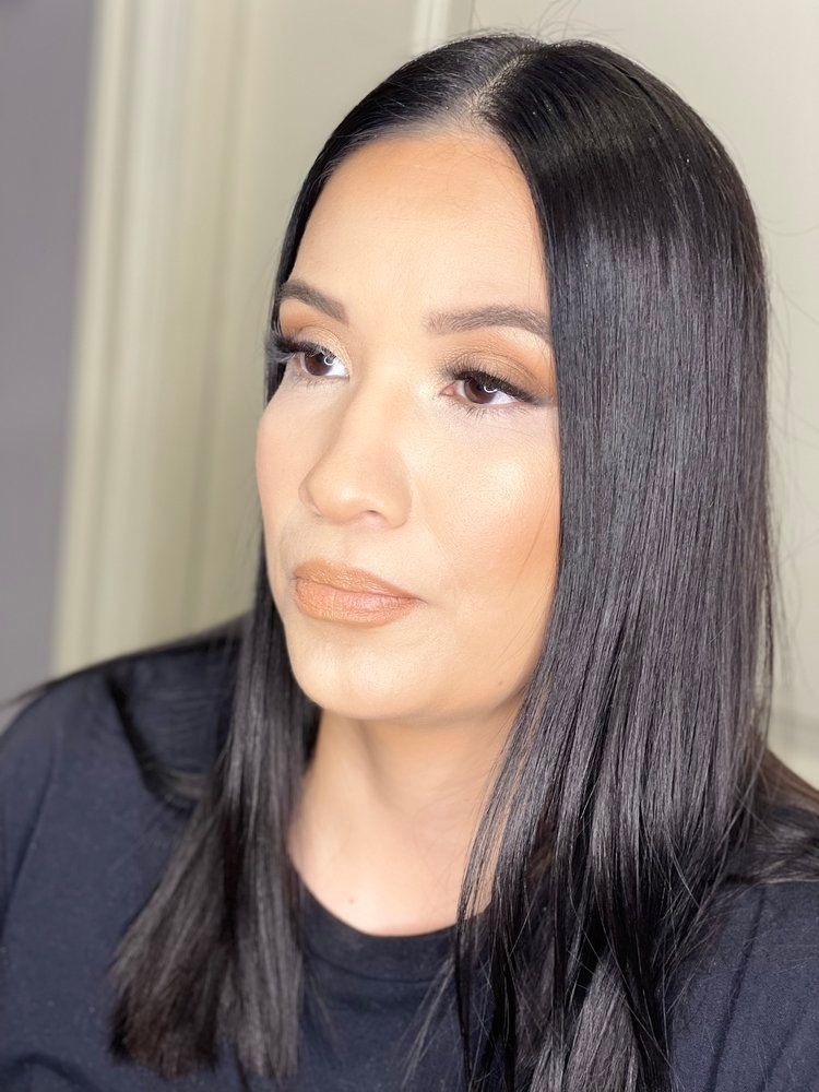 A woman with long black hair is wearing a black shirt and looking at the camera.