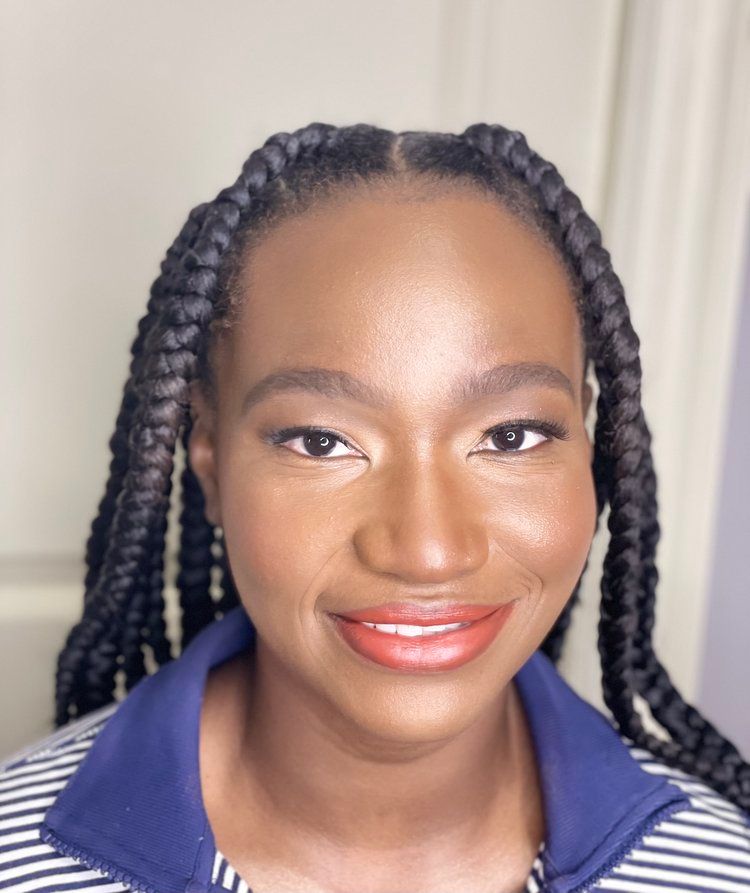 A woman with braids and red lipstick is wearing a blue and white striped shirt.