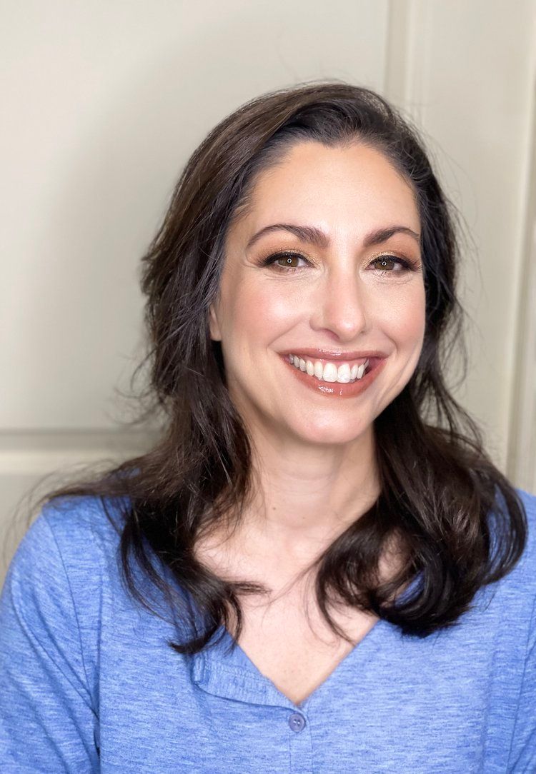 A woman in a blue shirt is smiling for the camera.