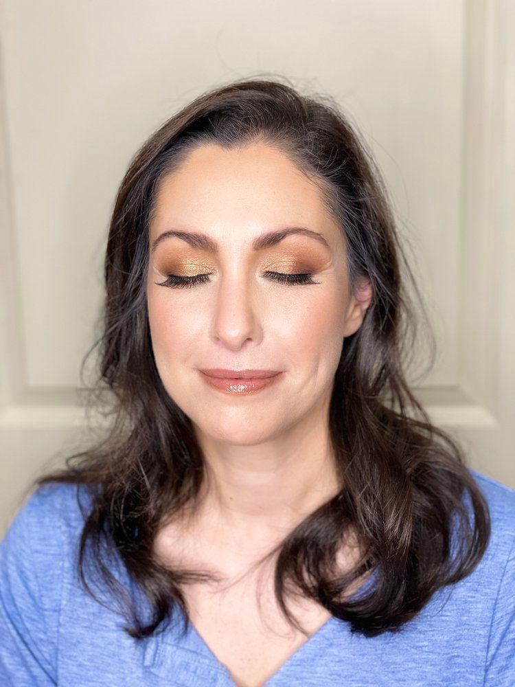 The woman is wearing a blue shirt and has her eyes closed.