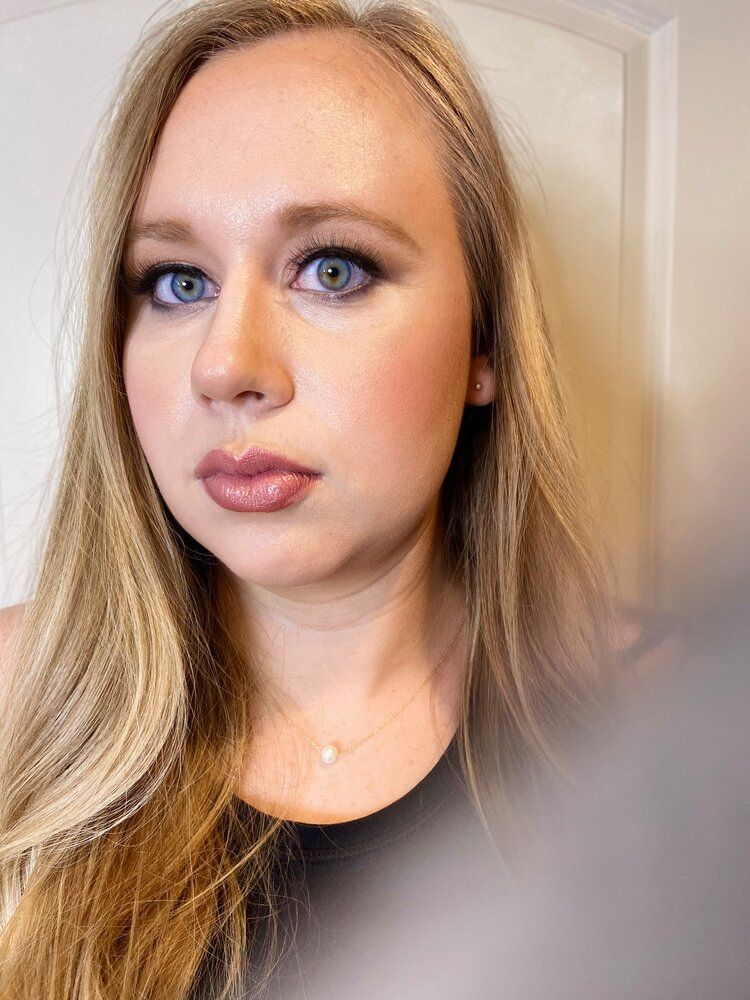 A woman with long blonde hair and blue eyes is looking at the camera.