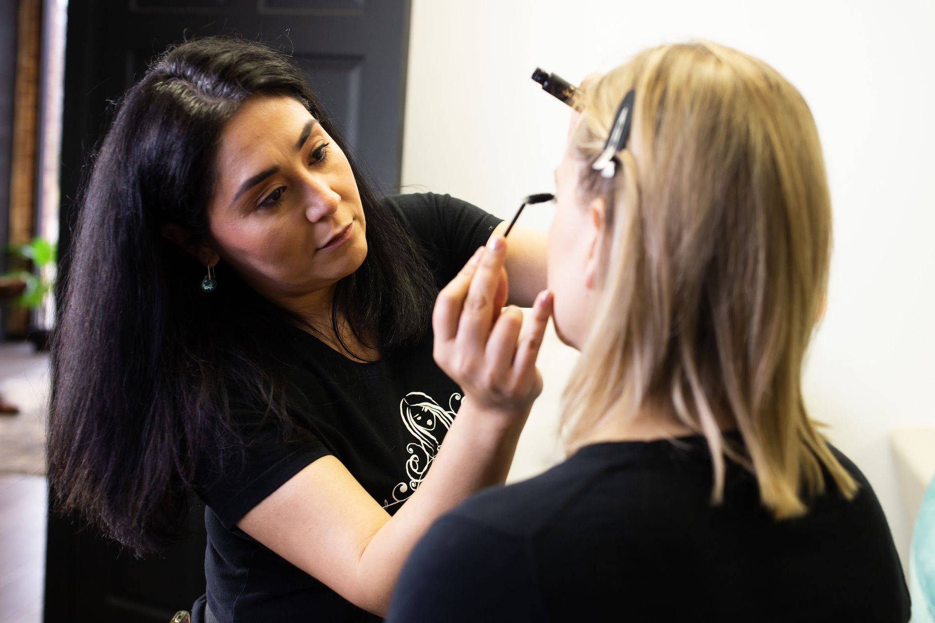 A woman is applying makeup to another woman 's face.