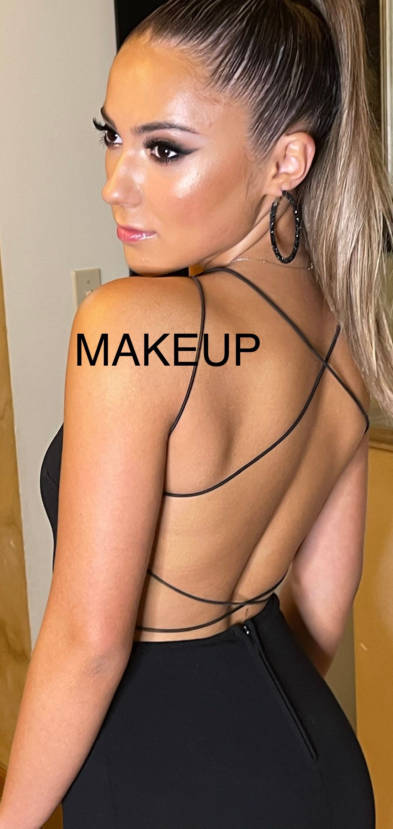A woman in a black dress with the word makeup on her shoulder.