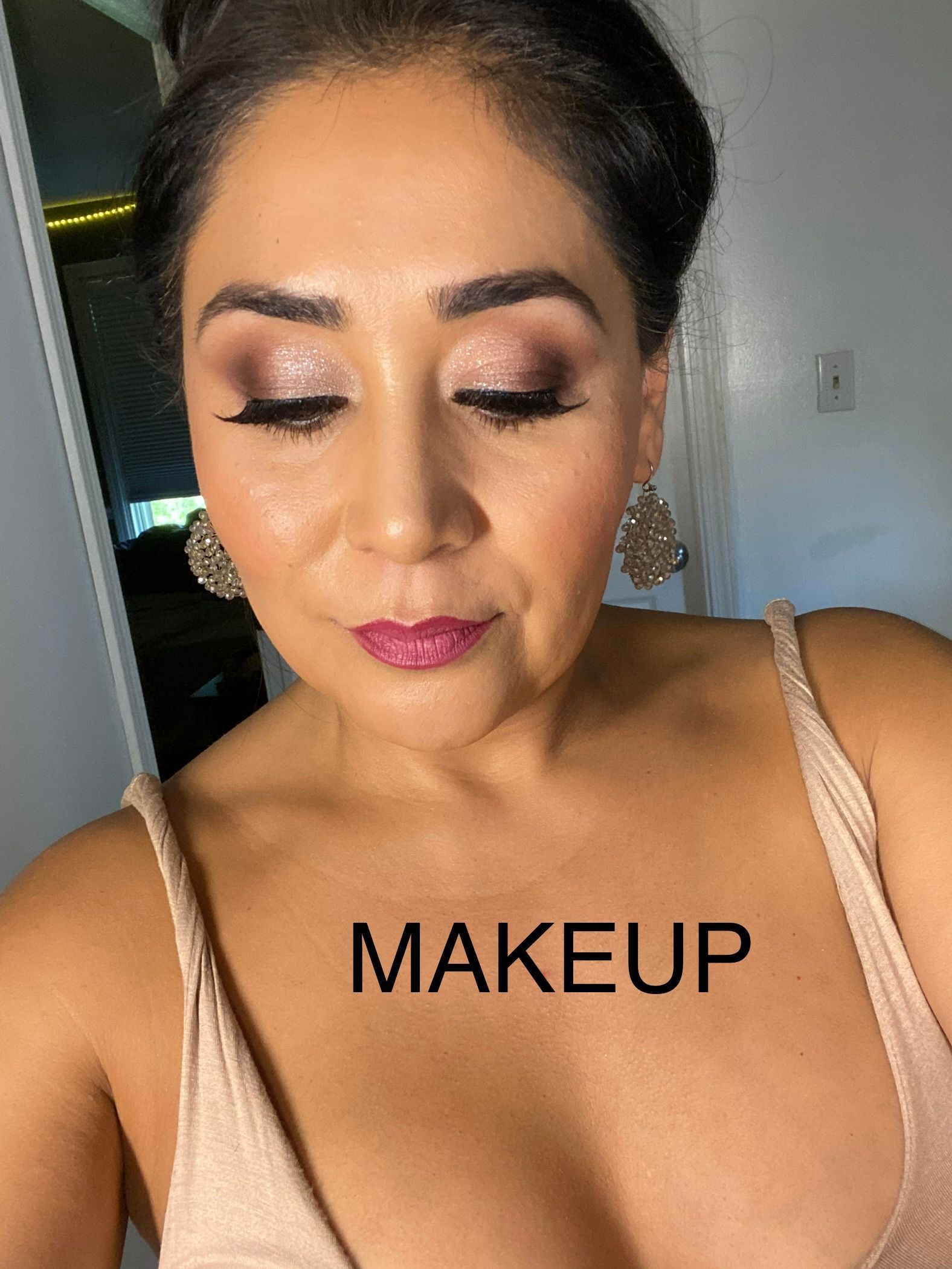 A woman is taking a selfie with the word makeup on her chest.