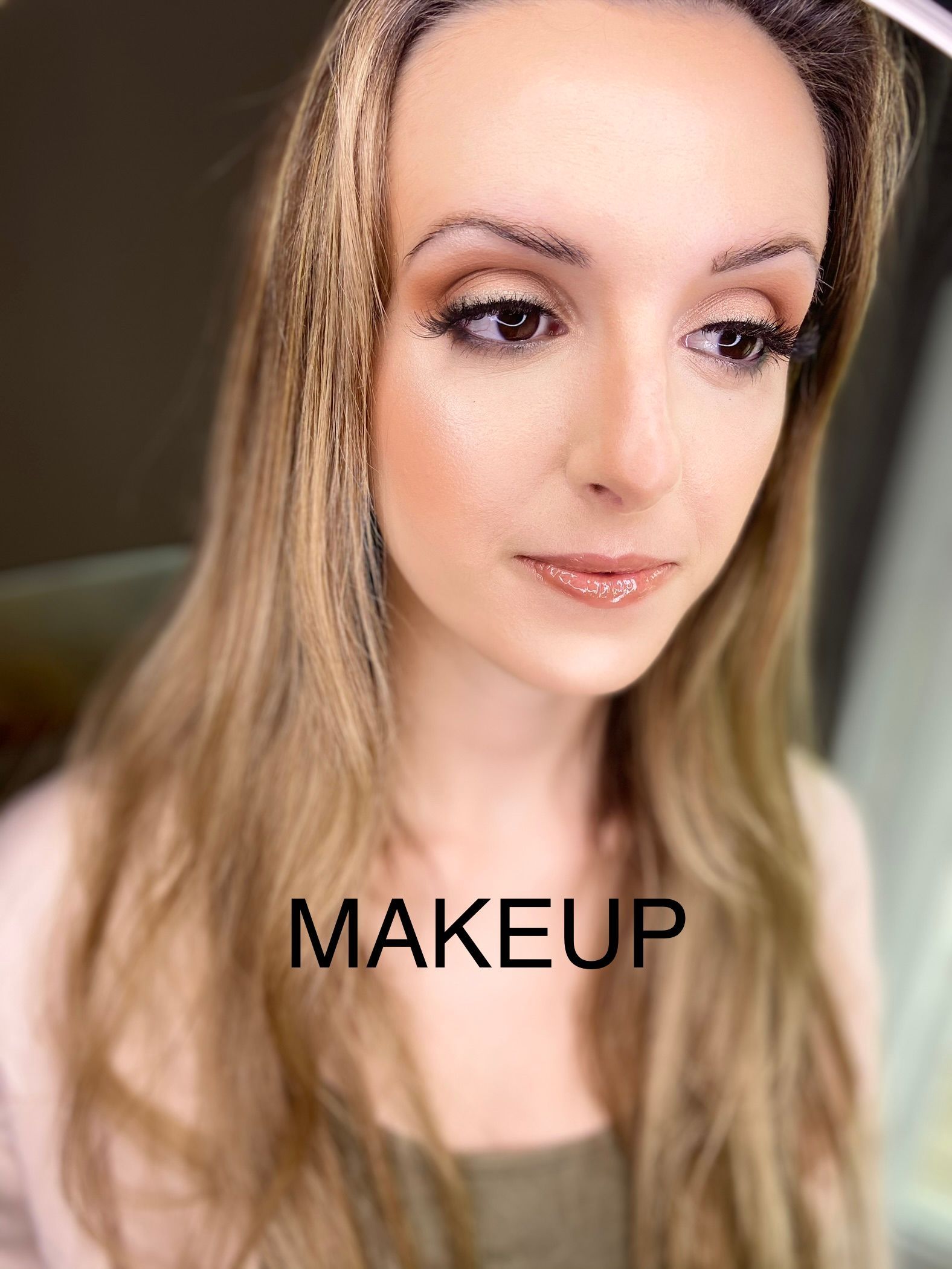 A woman with long hair is wearing makeup and looking at the camera.