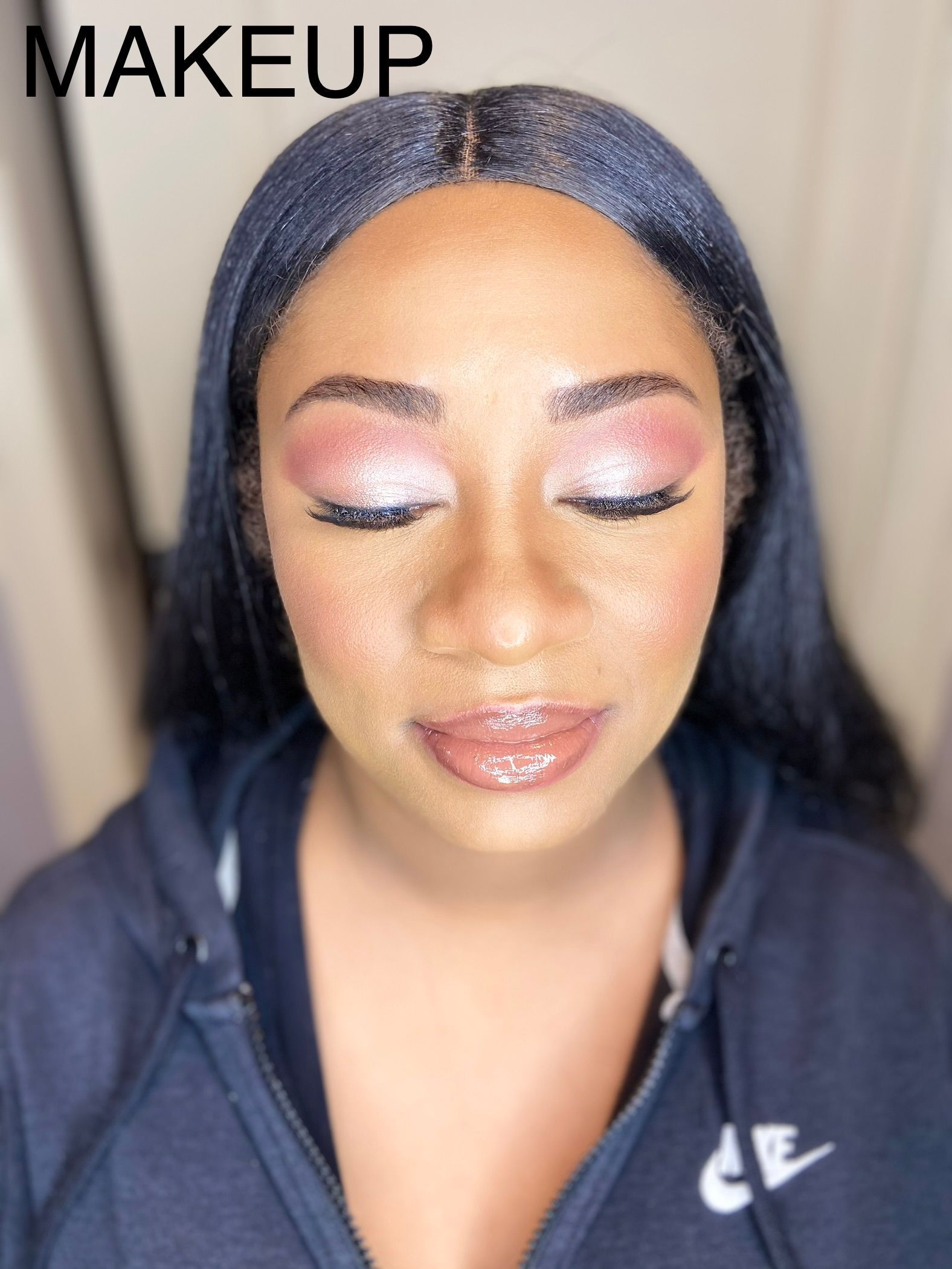 A woman wearing a blue nike hoodie has makeup on her face.