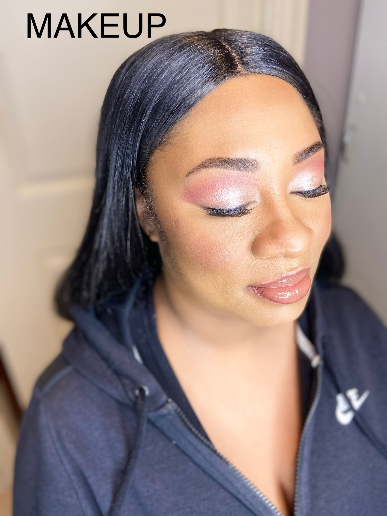 A woman with makeup on her face is wearing a black hoodie.