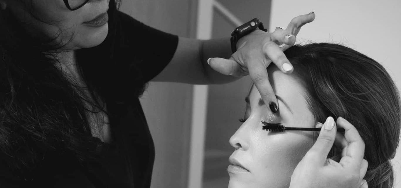 A woman is applying mascara to another woman 's eye.