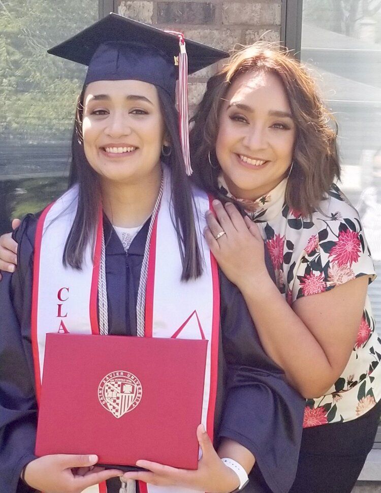 A woman in a graduation cap and gown holds a red diploma