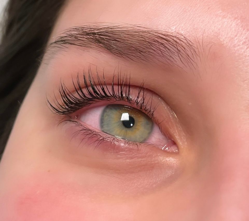 A close up of a woman 's green eye with long eyelashes.