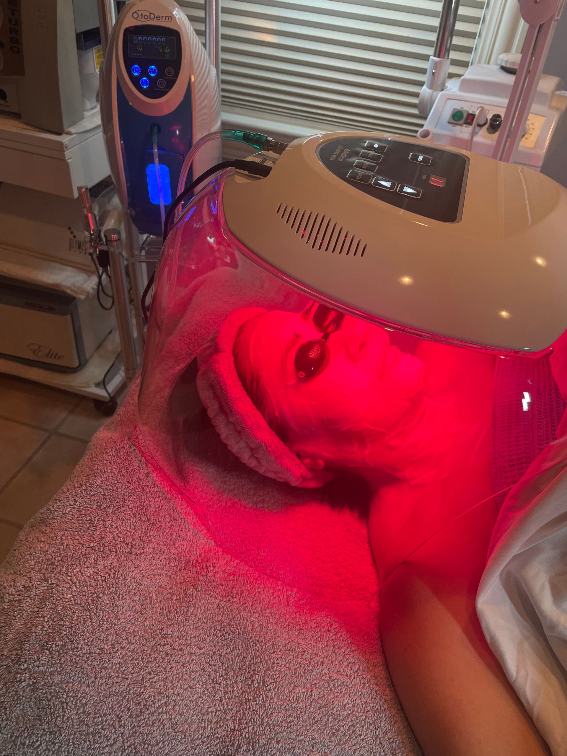 A woman is getting a red light treatment on her face.
