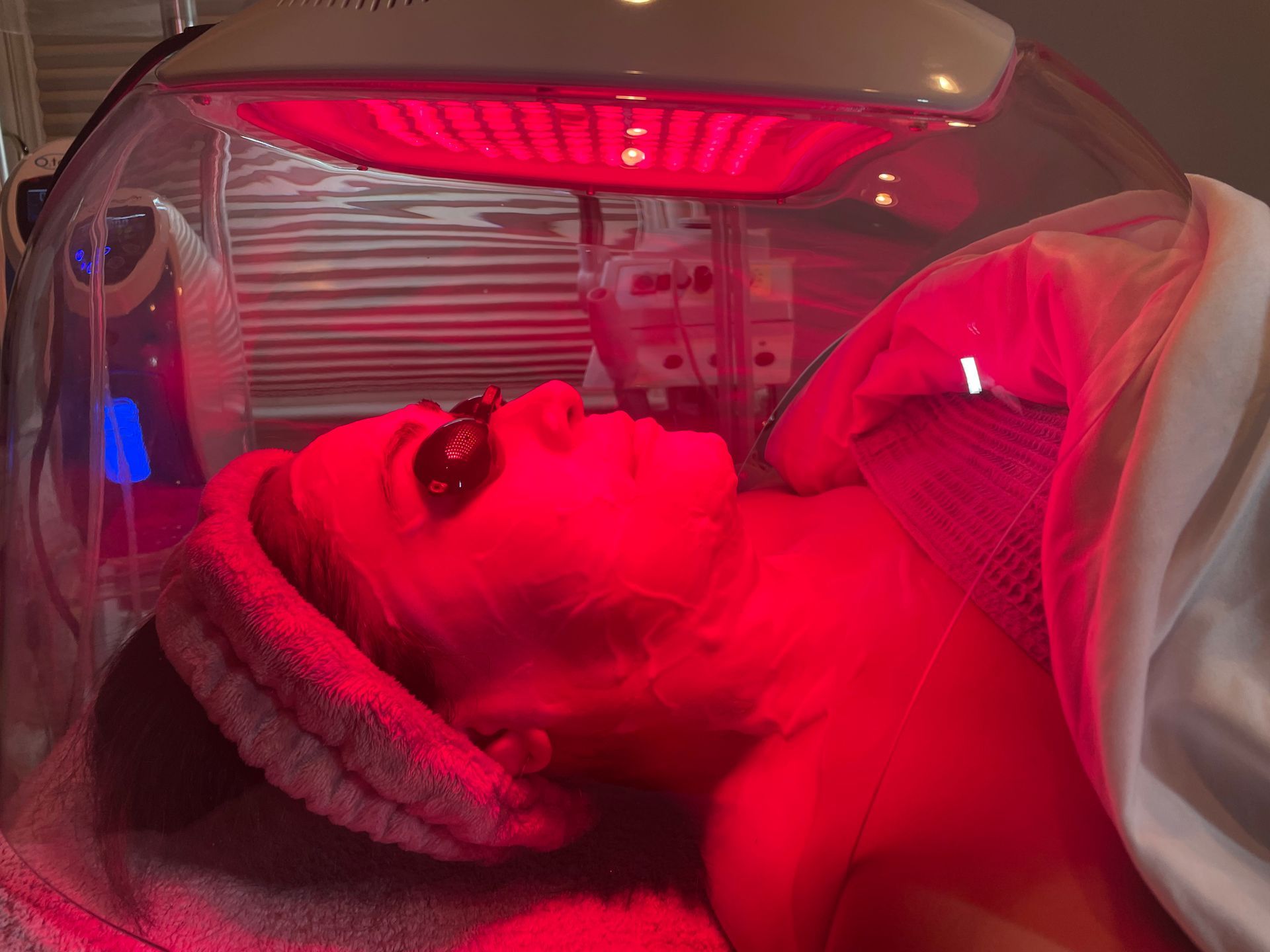 A woman is getting a red light treatment on her face.