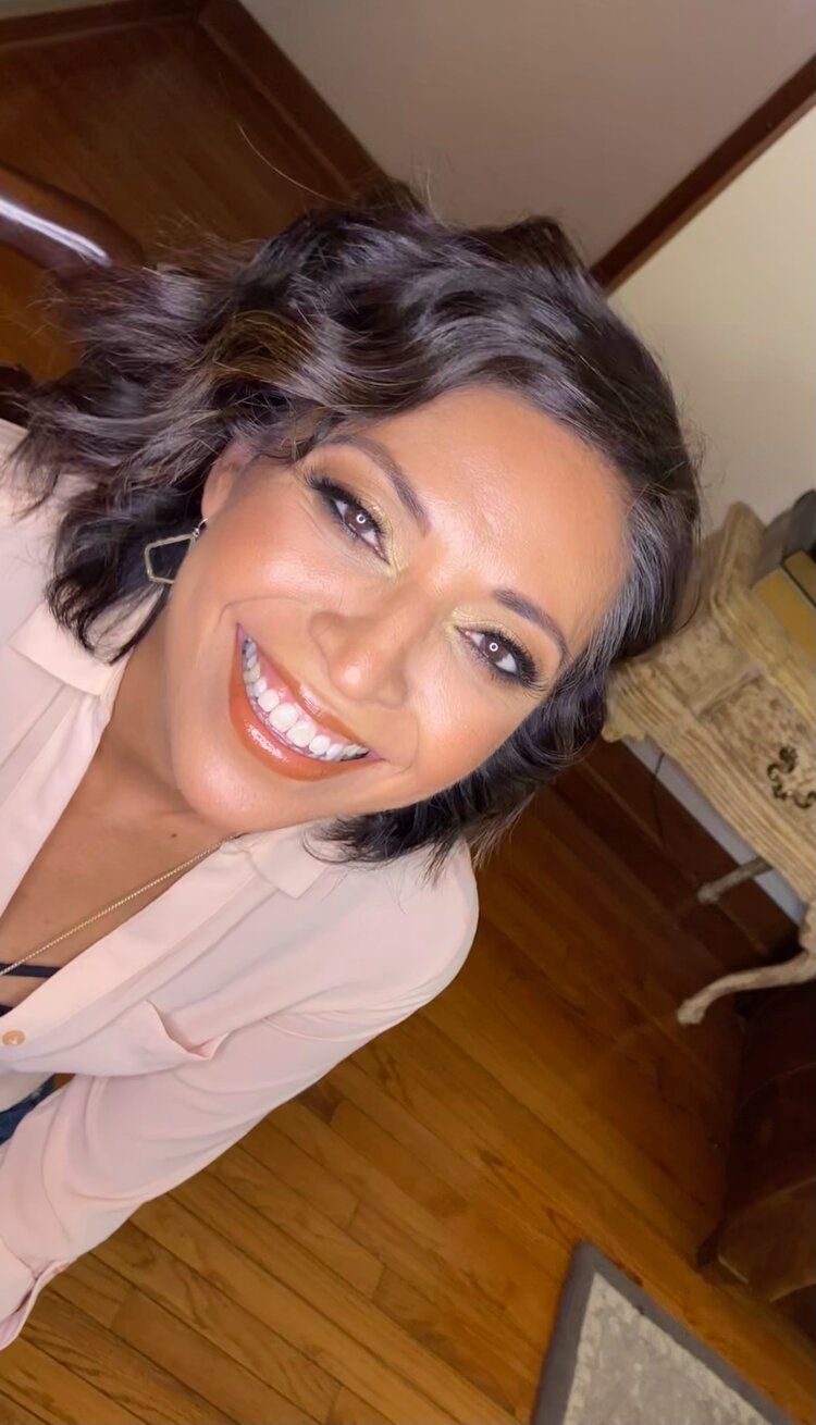 A woman is smiling while sitting on the floor in a room.