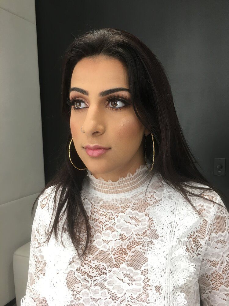 A woman is wearing a white lace top and hoop earrings.
