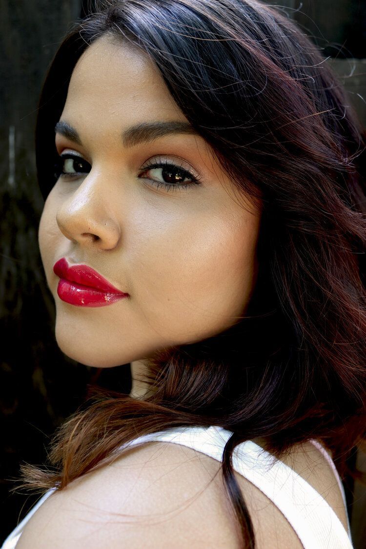 The woman is wearing red lipstick and a white tank top.