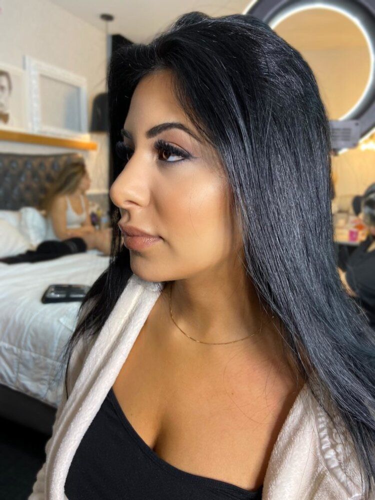 A woman with long black hair is standing in front of a mirror.