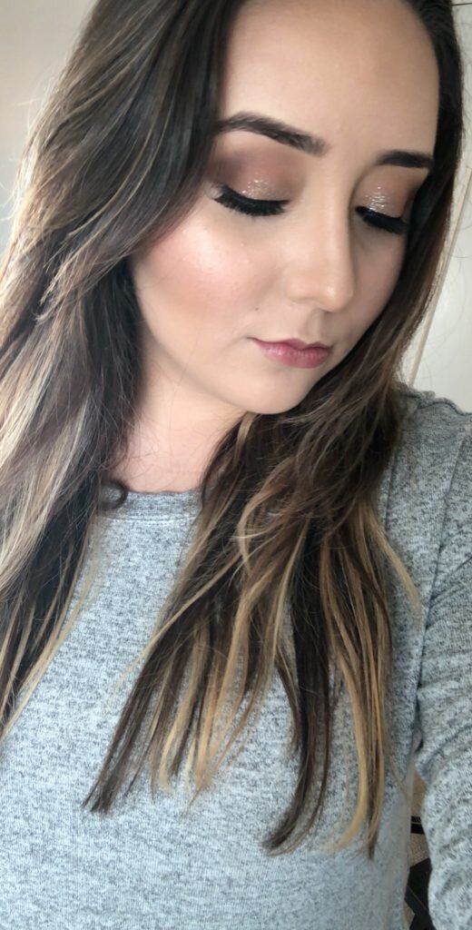 A close up of a woman taking a selfie with her eyes closed.