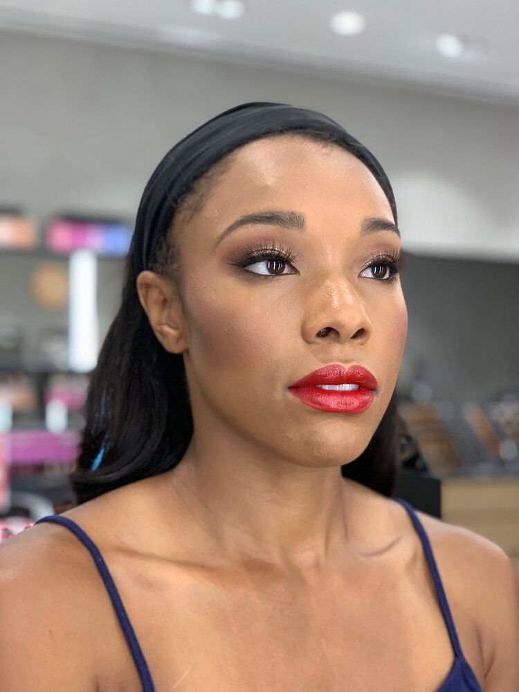 A woman wearing red lipstick and a headband is looking at the camera.