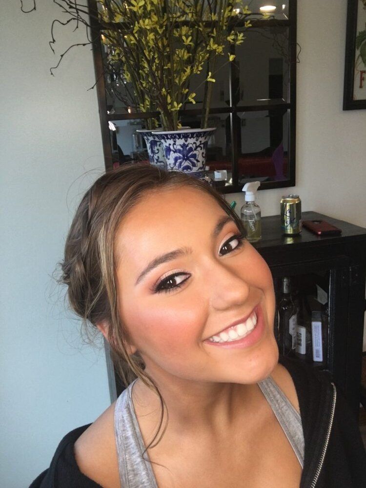 A woman is smiling in front of a mirror in a room