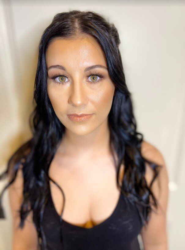 A woman with long black hair is wearing a black tank top.