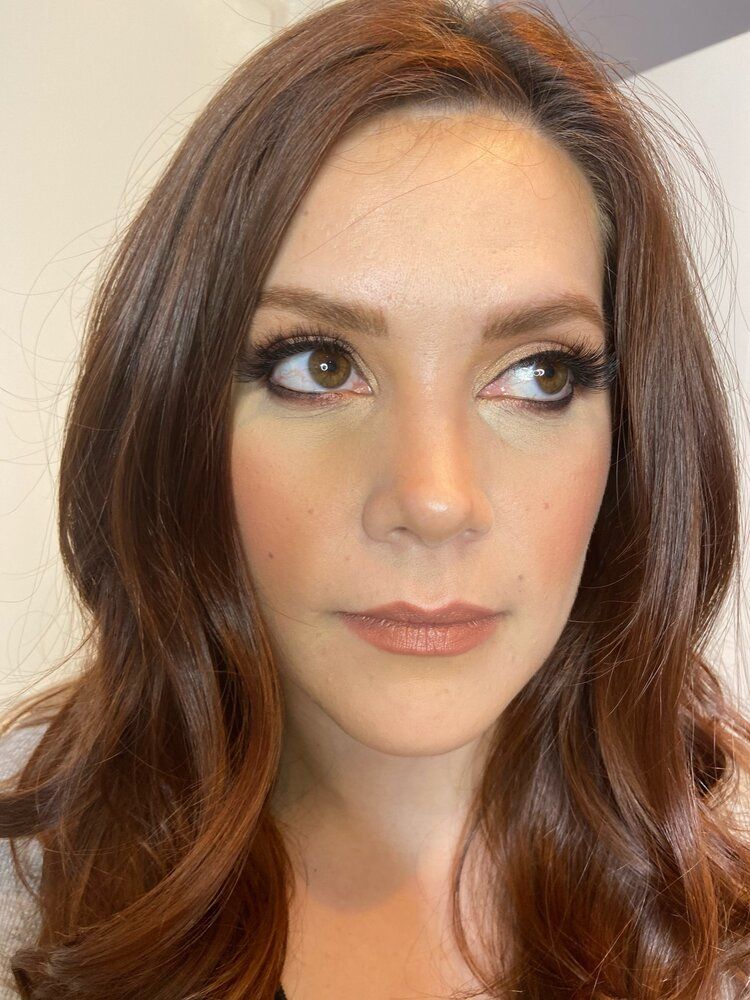 A close up of a woman 's face with long brown hair.