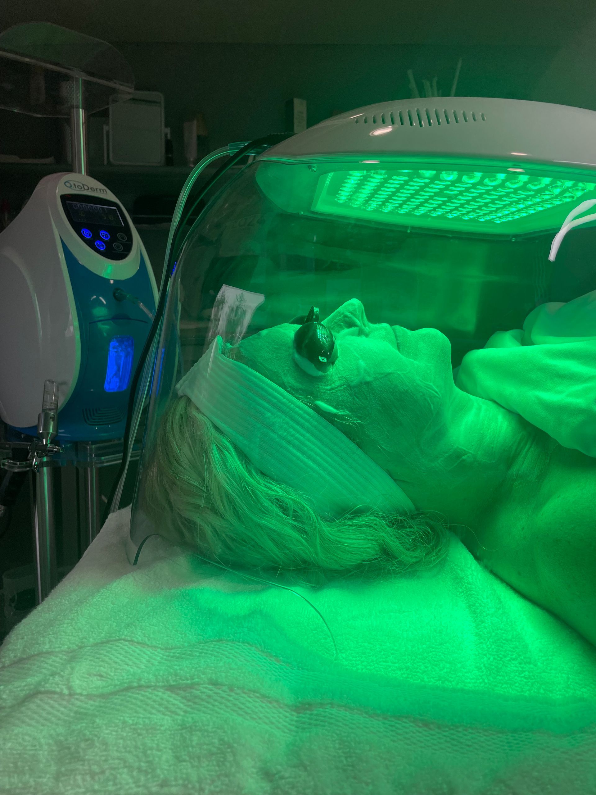 A woman is laying on a bed under a green light.