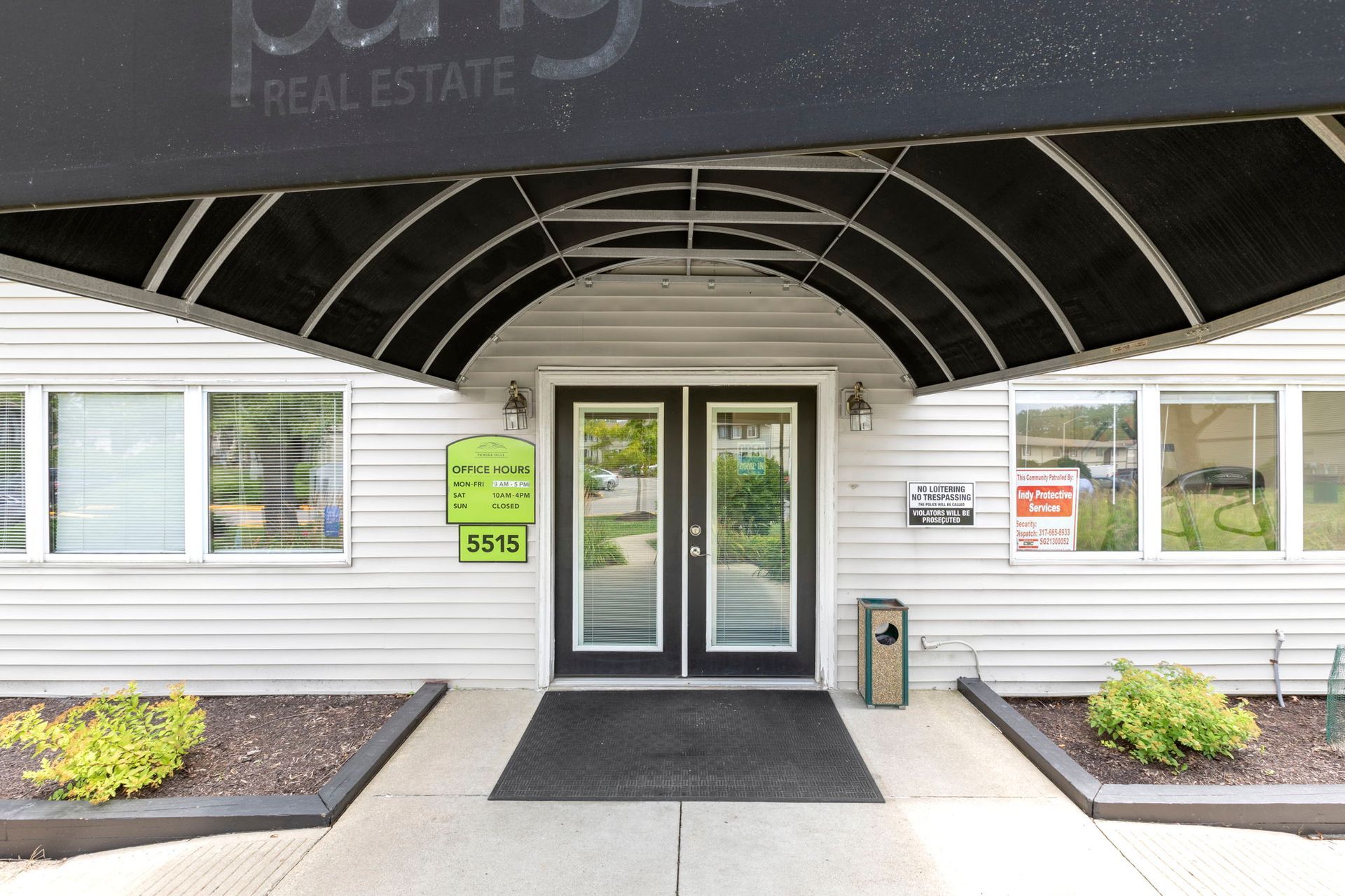Entrance to an apartment complex with a black awning and double glass doors.