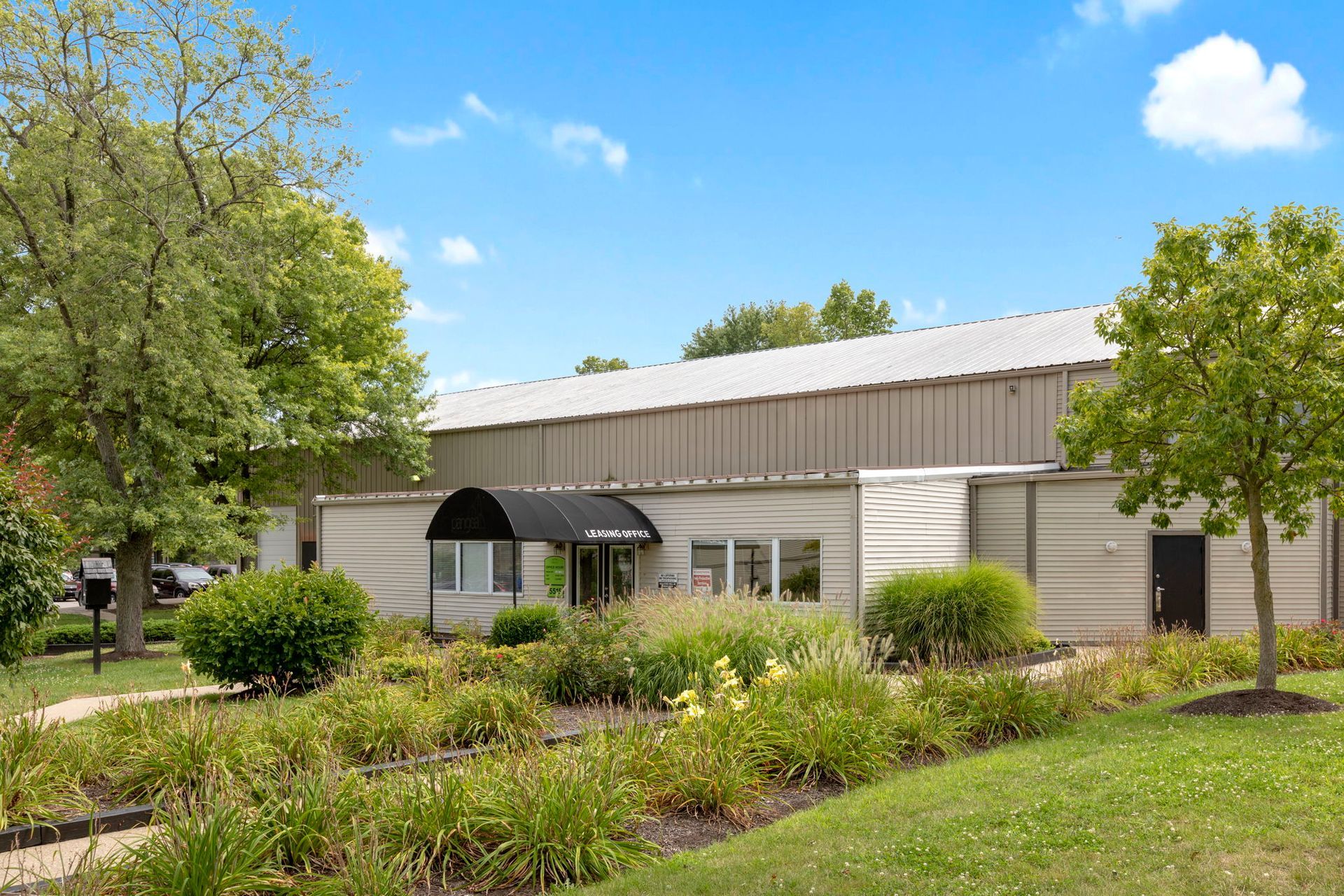 Exterior view of a commercial building with landscaping, trees, and blue sky.
