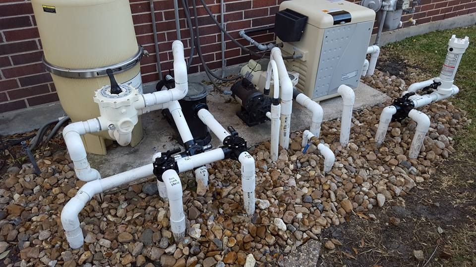 A bunch of pipes are sitting on the ground in front of a brick building.