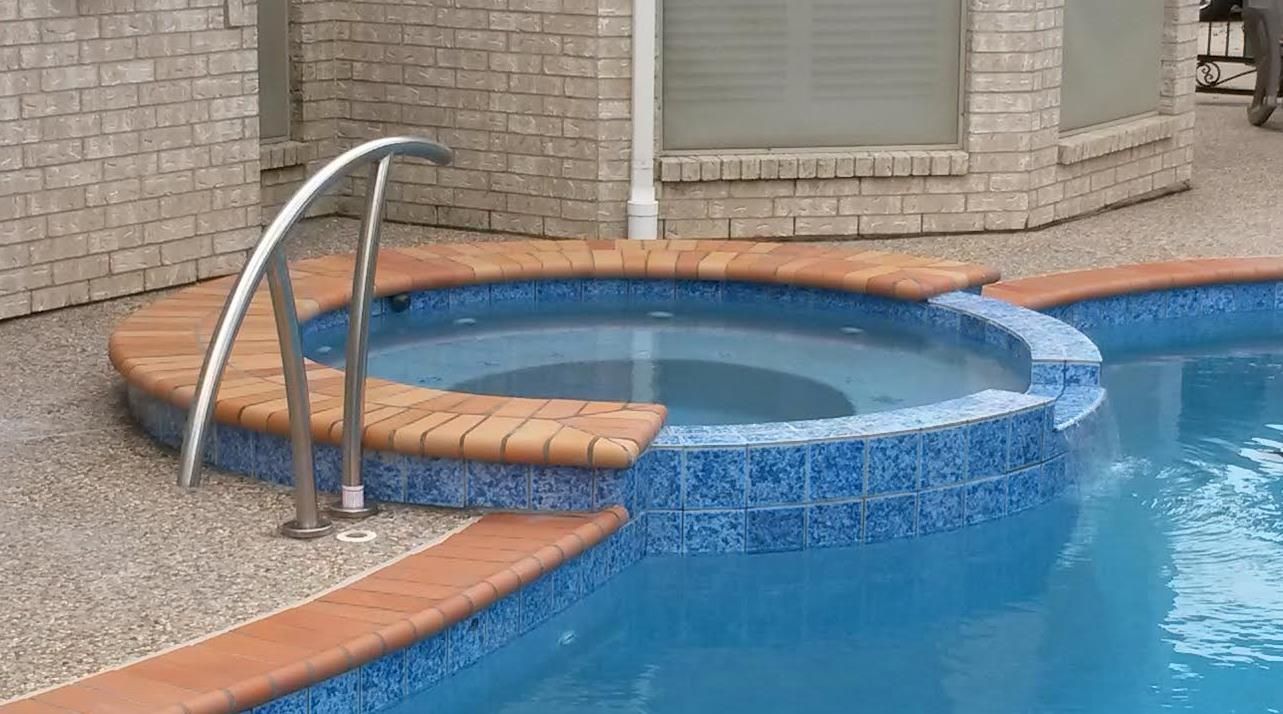 A swimming pool with a hot tub in the middle of it.