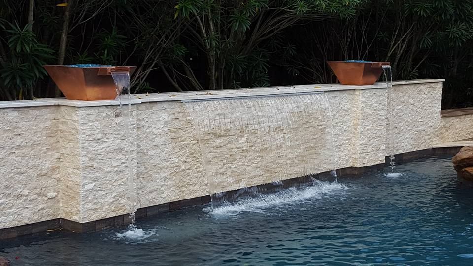 A swimming pool with a waterfall on the side of it.