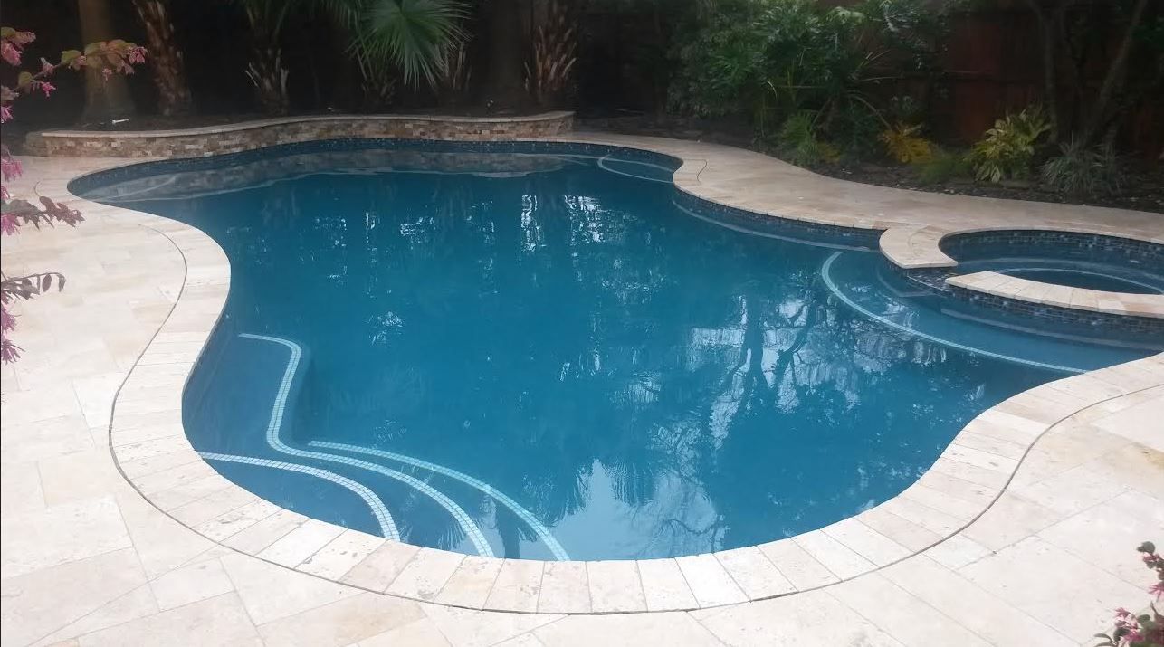 A large swimming pool with a hot tub in the backyard