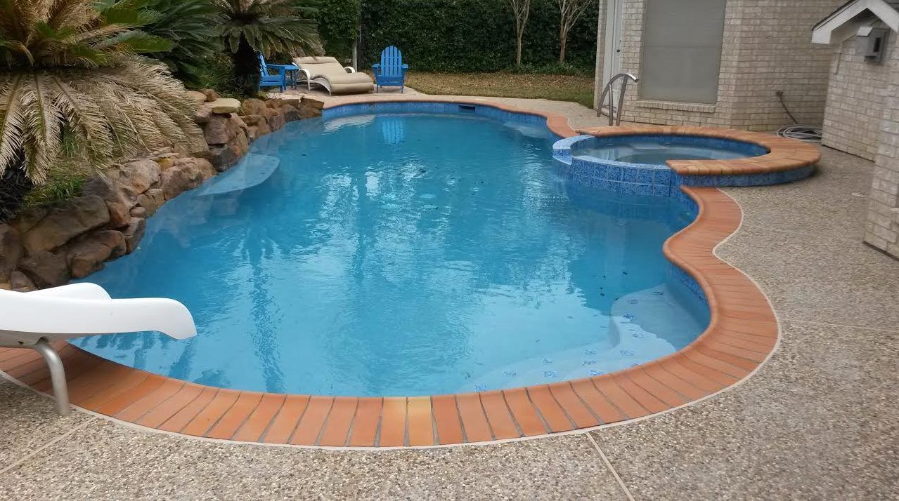 A large swimming pool with a slide and a hot tub in the backyard of a house.