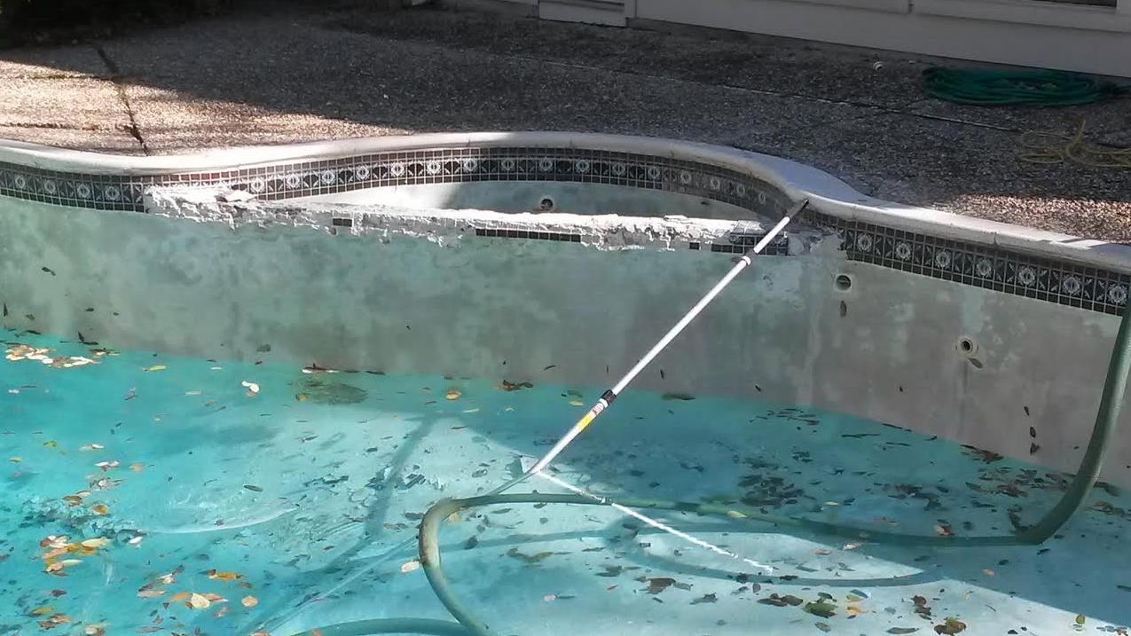A dirty swimming pool with a hose attached to it.