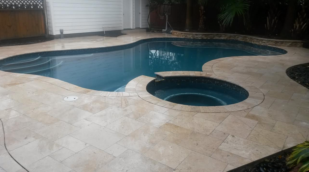 A large swimming pool with a hot tub in the middle of it.