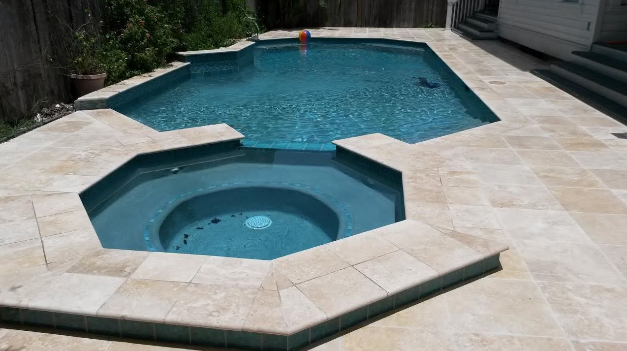 A large swimming pool with a hot tub in the middle.