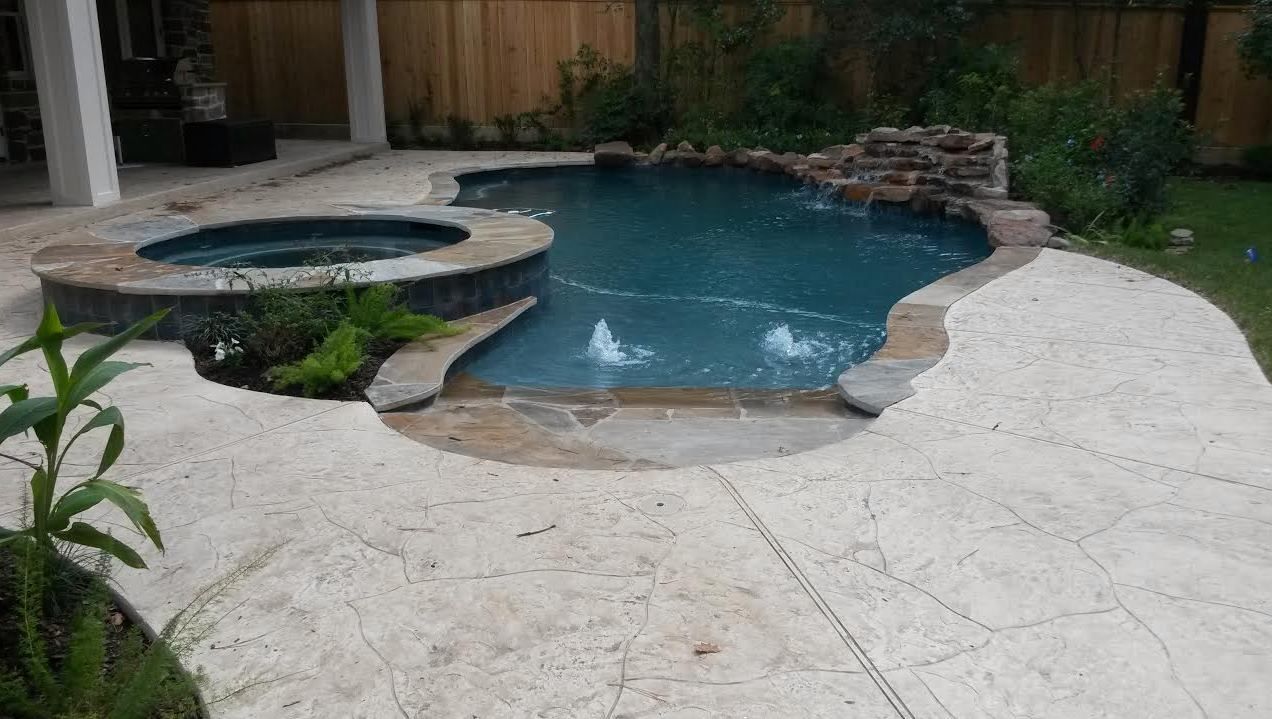 A large swimming pool with a hot tub in the backyard.