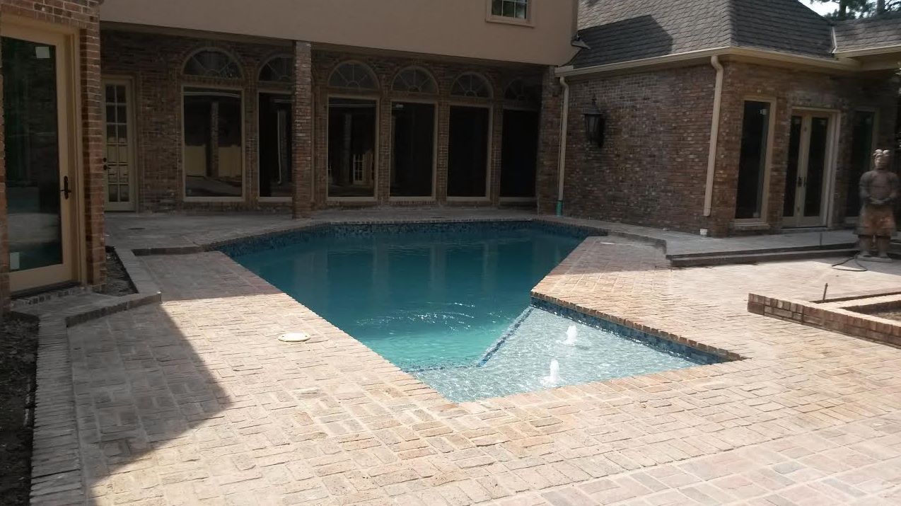 A large swimming pool is in the backyard of a house.