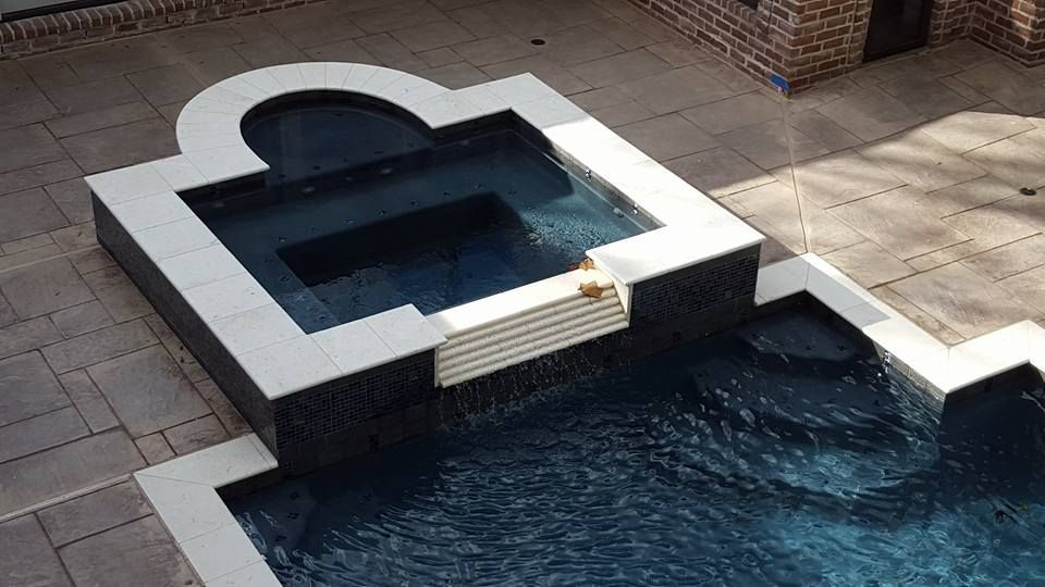 A large swimming pool with a hot tub in the middle of it.
