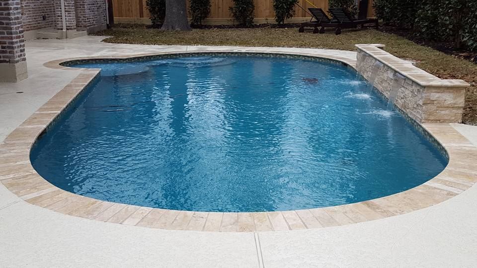 A large swimming pool in a backyard with a brick border