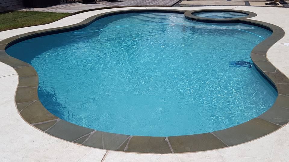 A large swimming pool with a hot tub in the middle