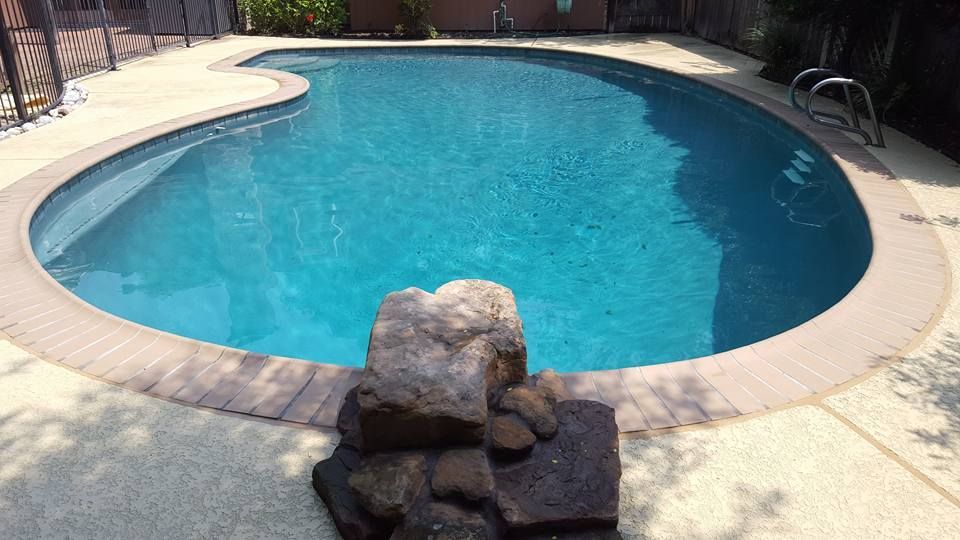 A large swimming pool with a rock in the middle of it.