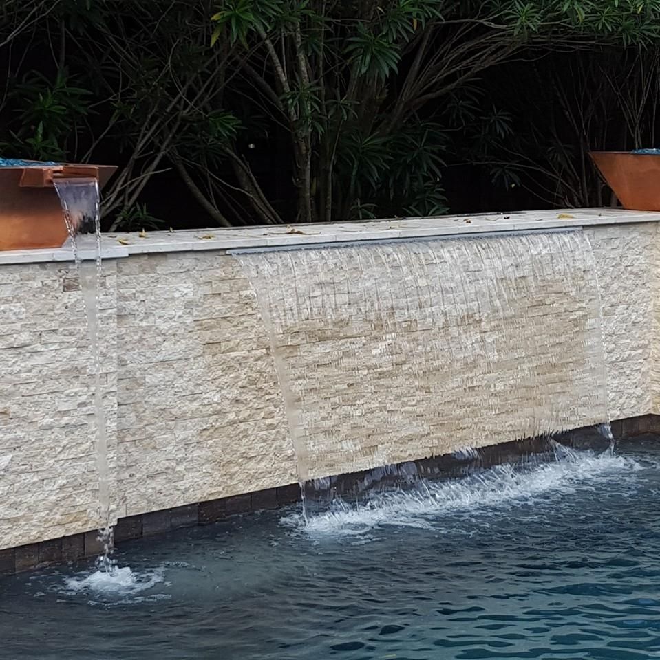 A swimming pool with a waterfall on the side of it