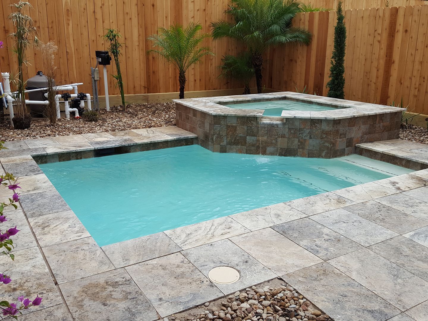A small swimming pool with a hot tub in the backyard.