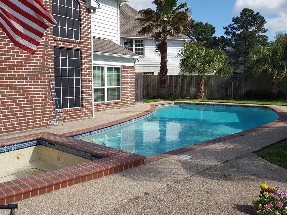 A large swimming pool in front of a brick house