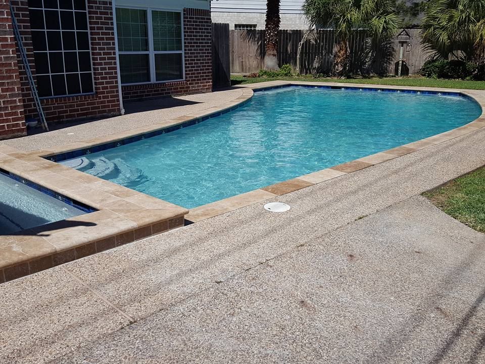 A large swimming pool is in the backyard of a house.