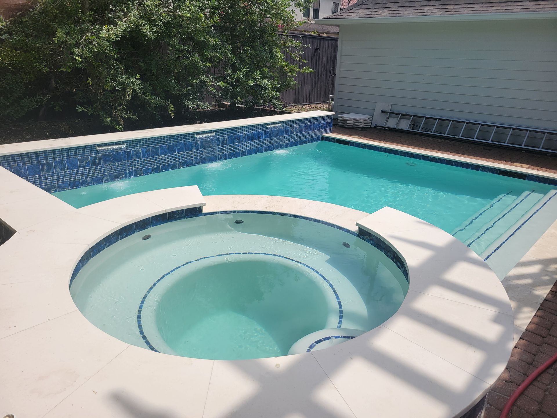 A large swimming pool is in the backyard of a house.