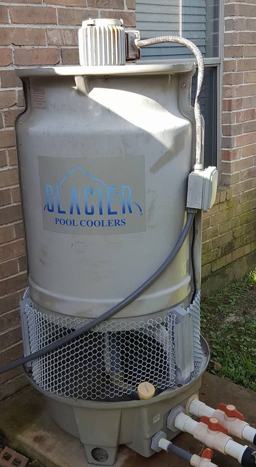 A large gray tank with a fan attached to it is sitting in front of a brick building.